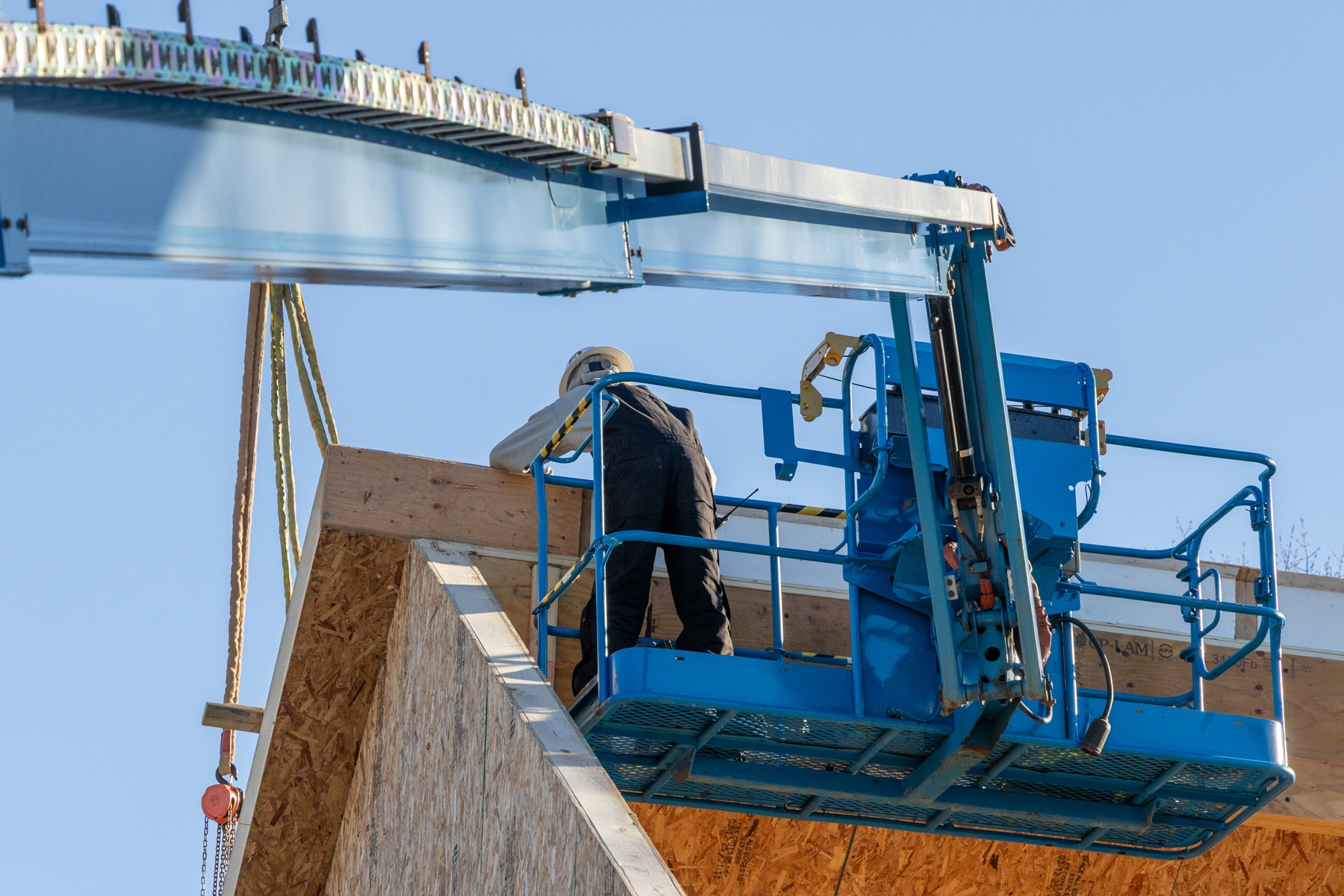 Construction crew on boom lift aligning roof panels