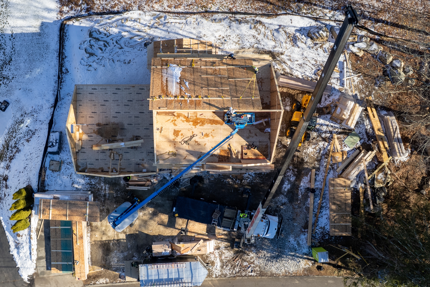 Crane truck hoisting SIP roof panel into place