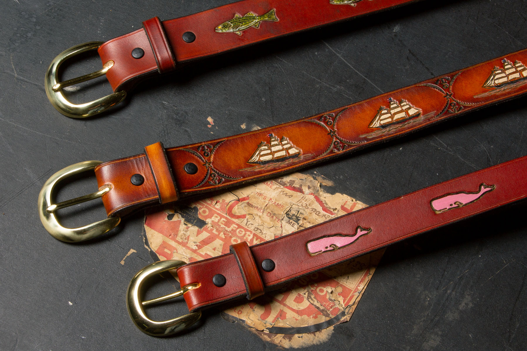Custom engraved and painted leather belts on old travel trunk