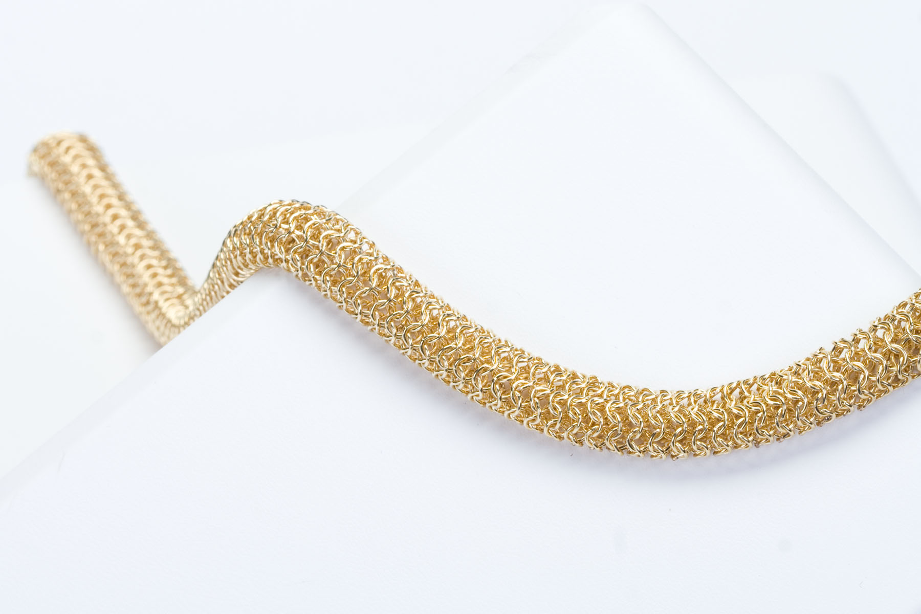 Luxury gold mesh necklace artfully curved around photography form