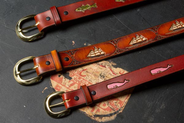 Custom engraved and painted leather belts on old travel trunk