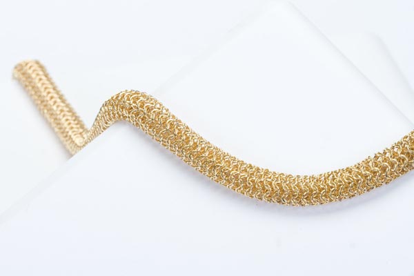 Luxury gold mesh necklace artfully curved around photography form