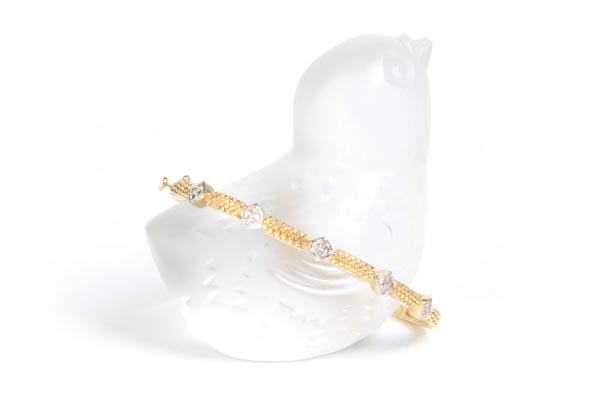 Diamond and gold bracelet resting on a translucent bird statue